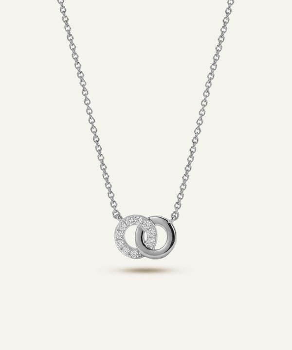 Silver necklace with interlocking rings pendant on a light gray background
