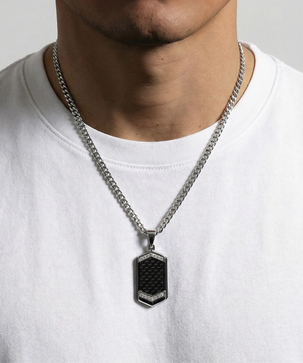 Person wearing a silver chain necklace with a black pendant on a white background