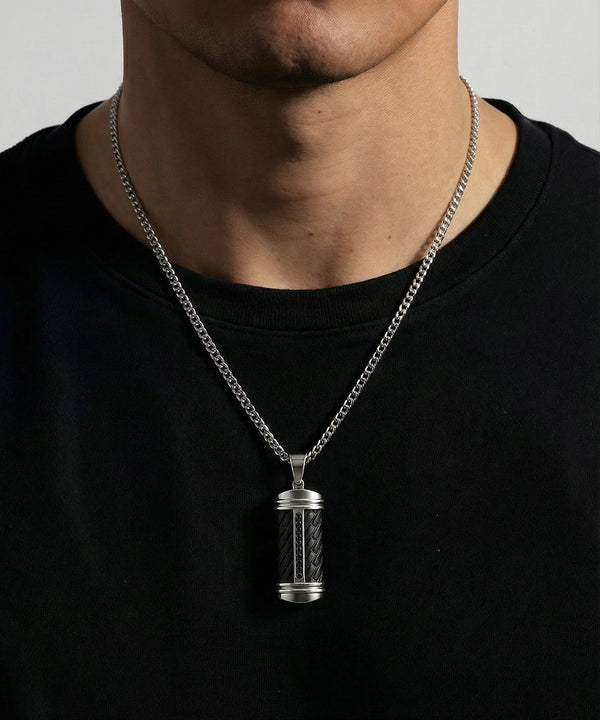 Silver pendant necklace on a person wearing a black shirt against a neutral background