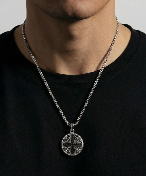 Silver necklace with a round pendant worn by a person on a plain background
