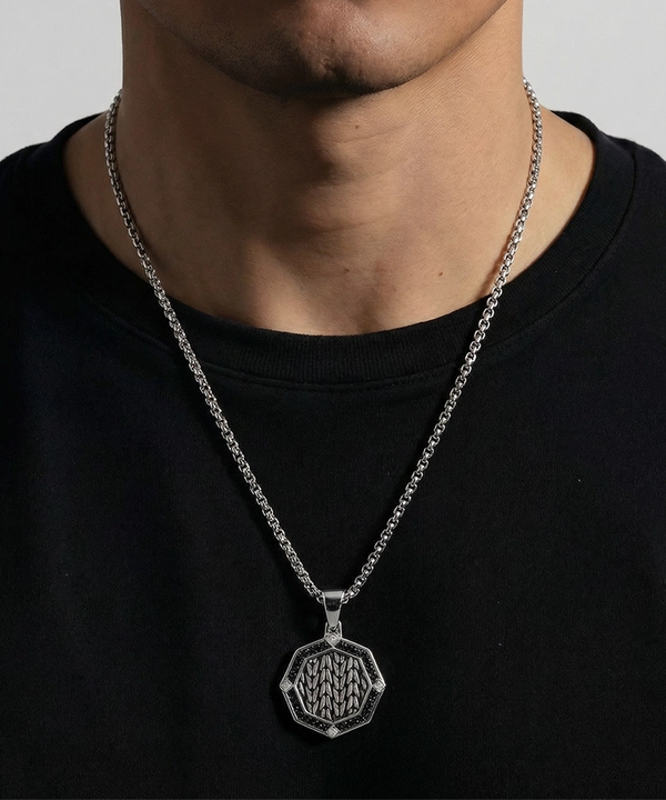 Silver necklace with a pendant worn by a person on a plain background
