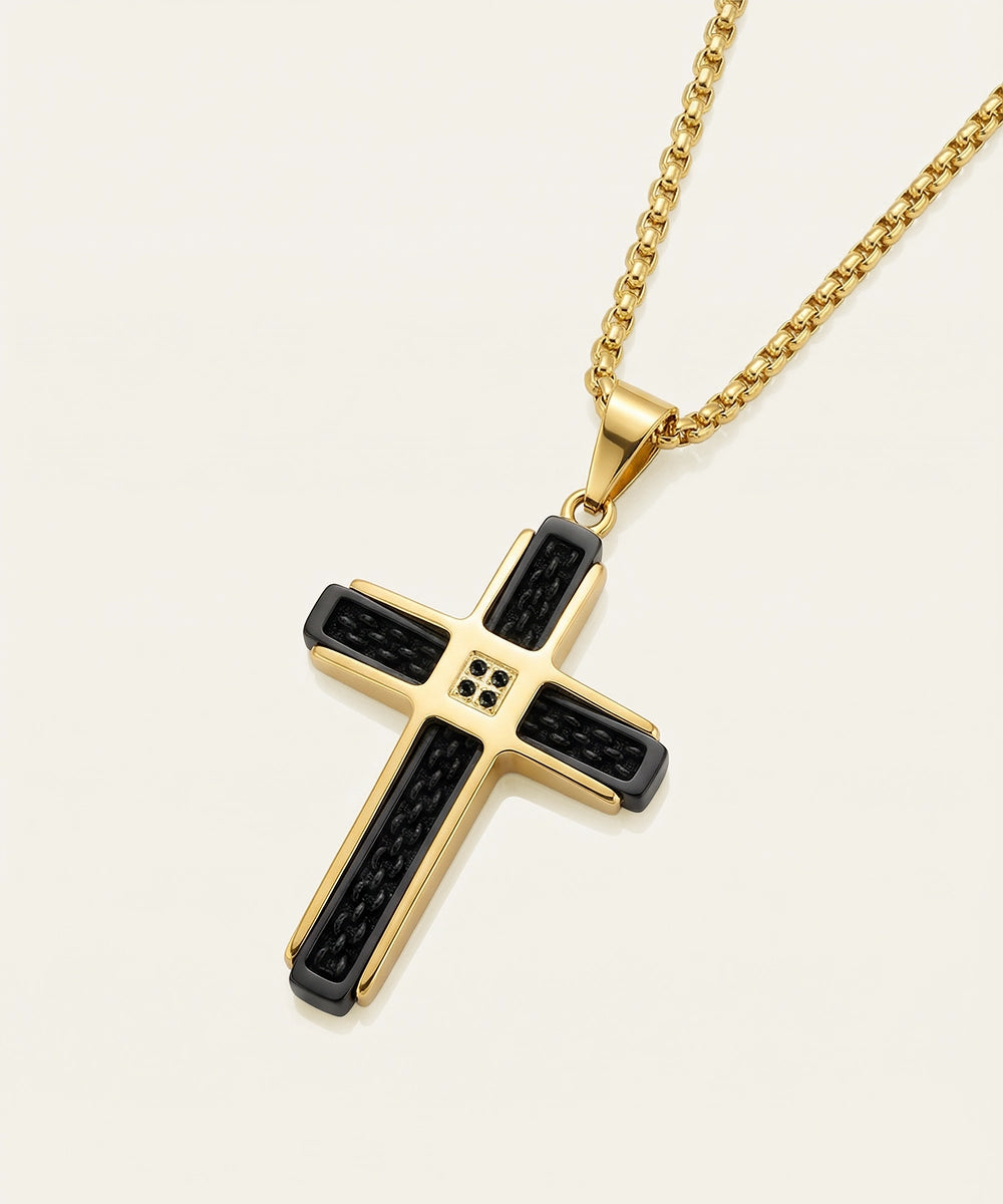 Gold cross pendant with black accents on a white background