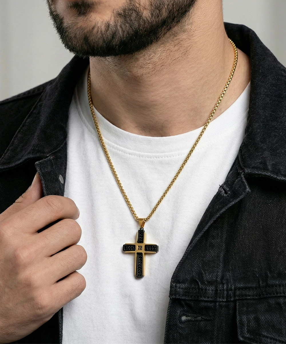 Man wearing a gold necklace with a cross pendant on a plain background