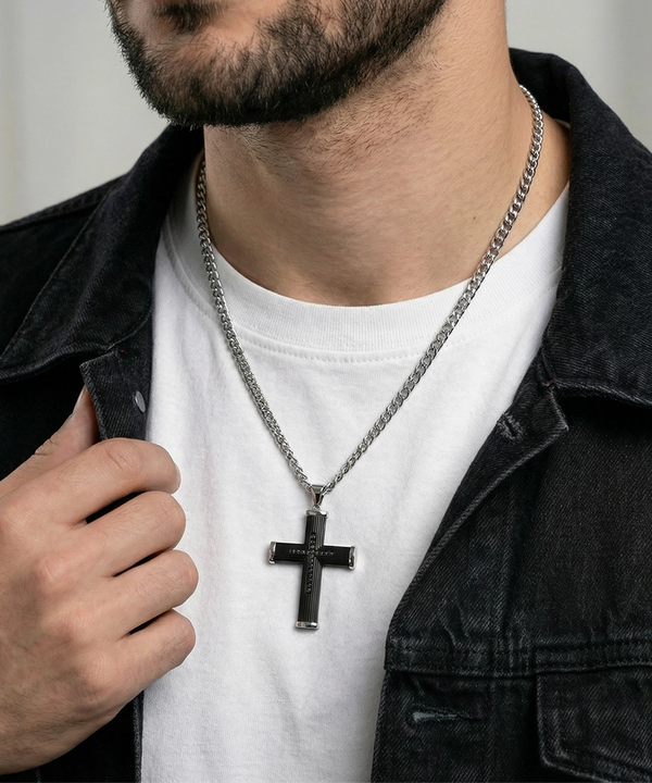 Man wearing a gold necklace with a cross pendant on a plain background