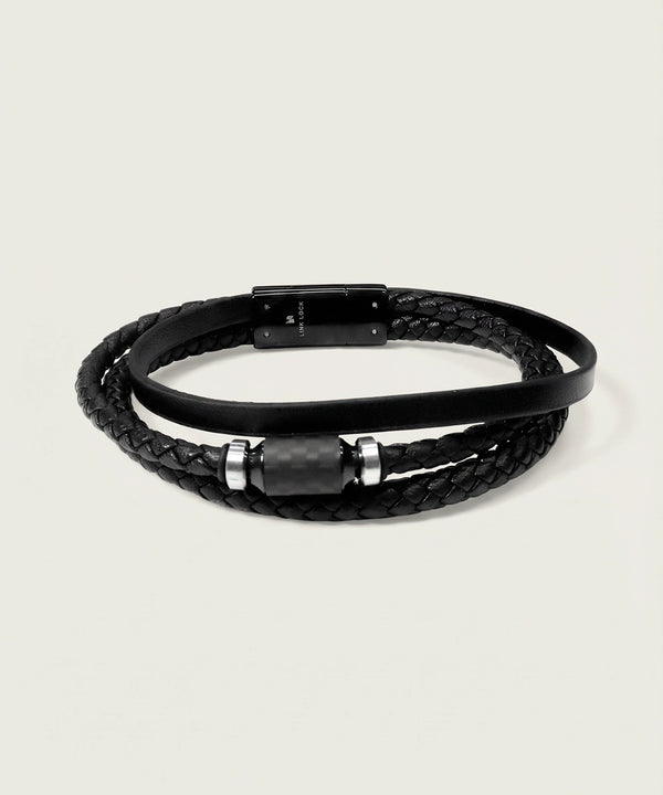 Black braided leather bracelet with metal accents on a light gray background