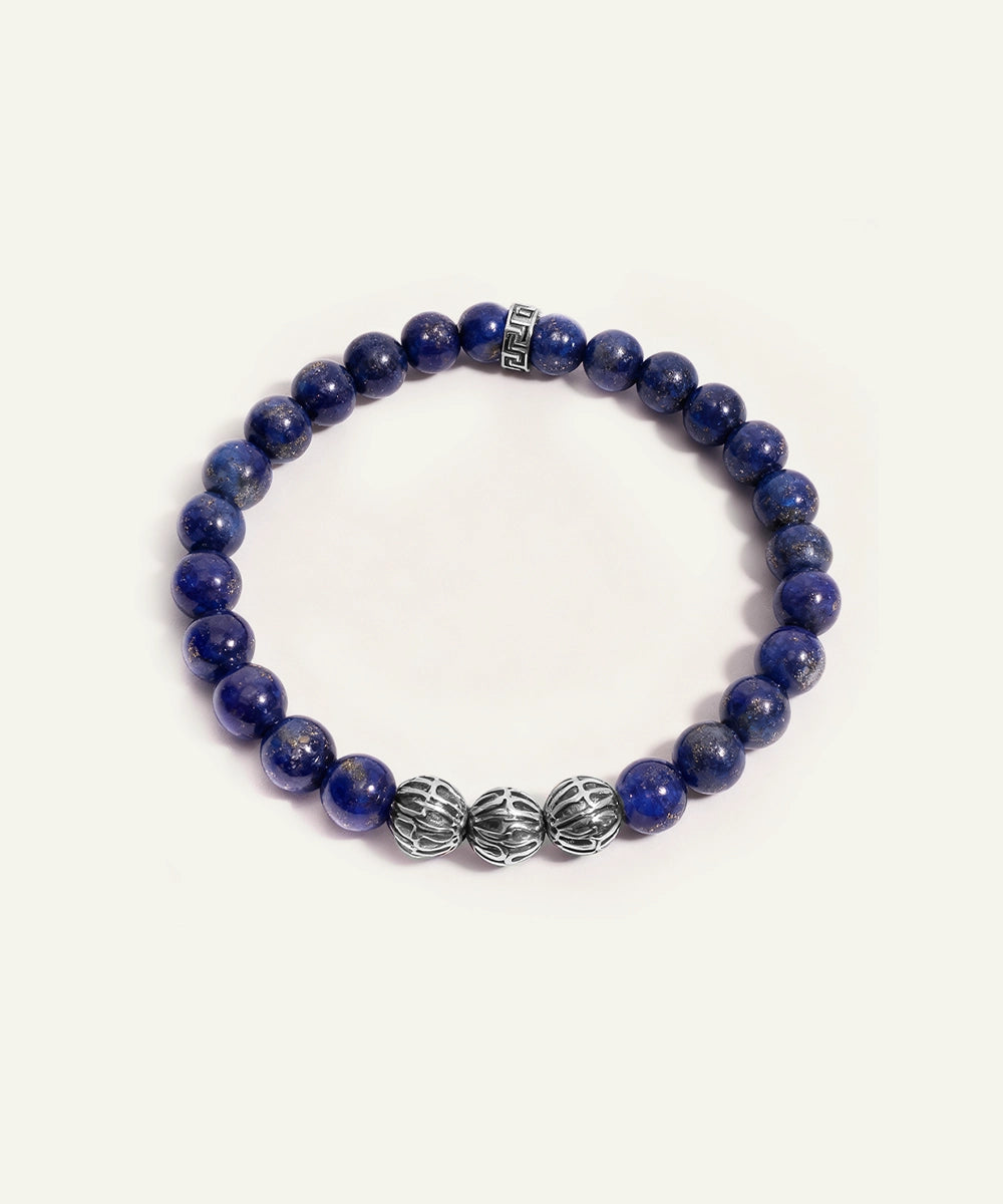 Blue beaded bracelet with silver charms on a white background