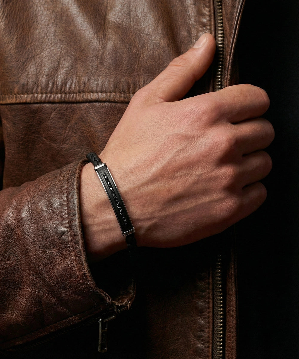 Hand wearing a black bracelet on a brown leather jacket background