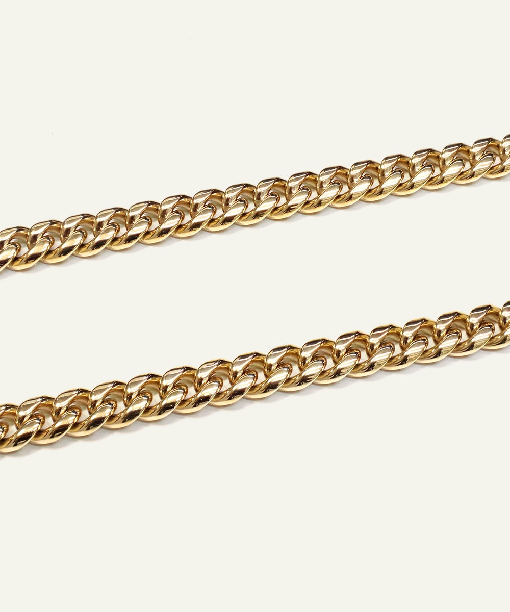 Two gold chain necklaces on a light beige background
