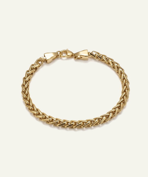 Gold braided bracelet on a light beige background