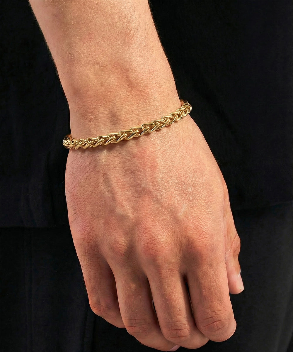 Gold braided bracelet on a person's wrist against a black background