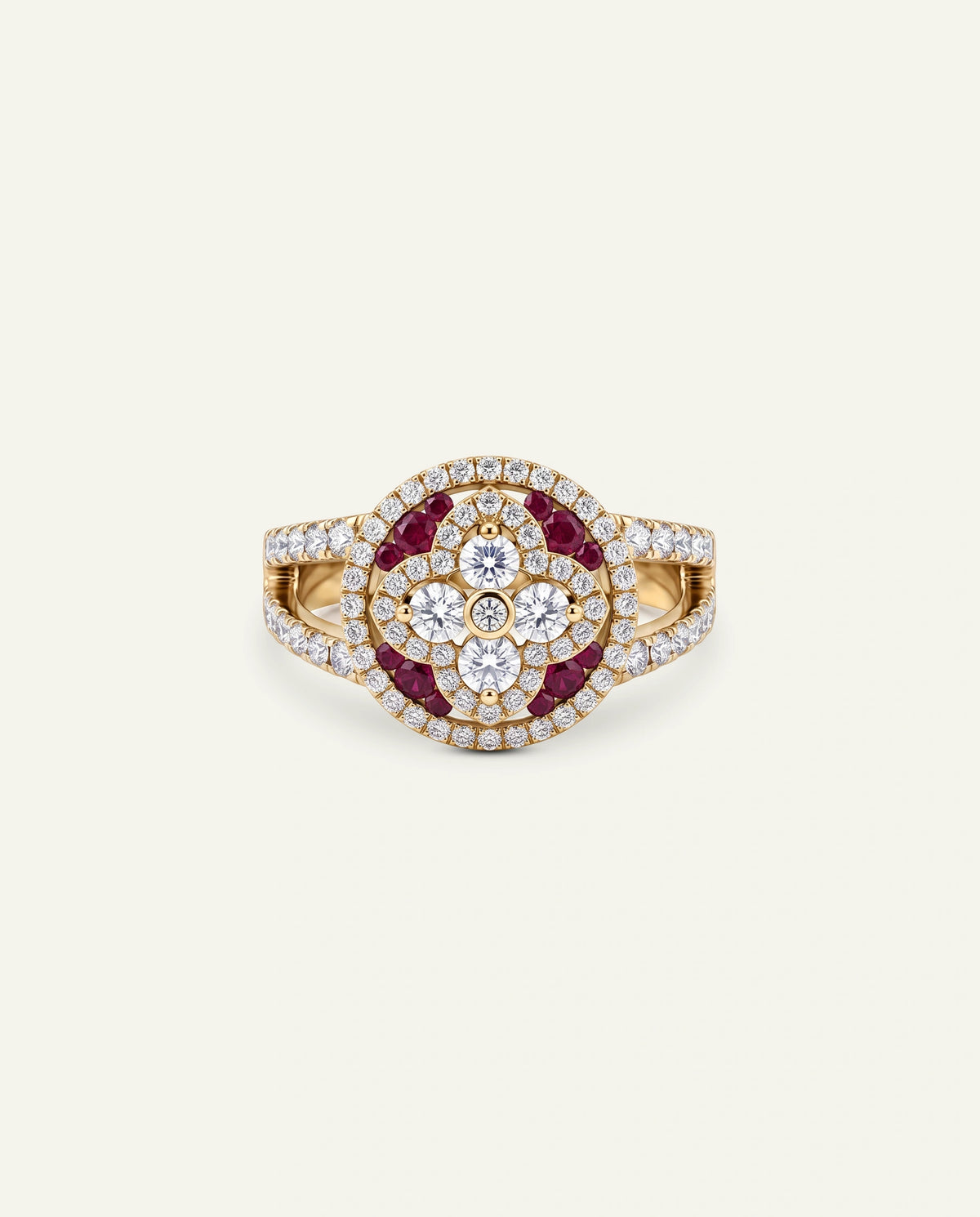 A gold ring featuring a circular floral cluster with dark red ruby stones, surrounded by clear cubic zirconia, with a matching diamond-patterned halo and shank, set against a light cream background.