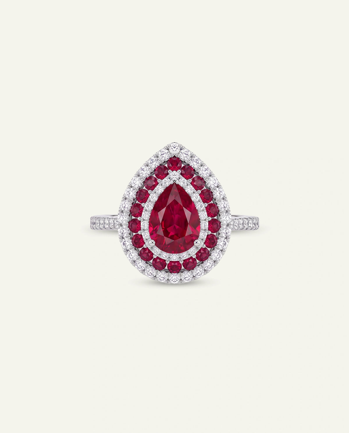 A teardrop-shaped ring featuring a central pear-cut ruby gemstone surrounded by a double halo of round red gemstones and small clear stones on a silver-toned band, set against a light cream background.