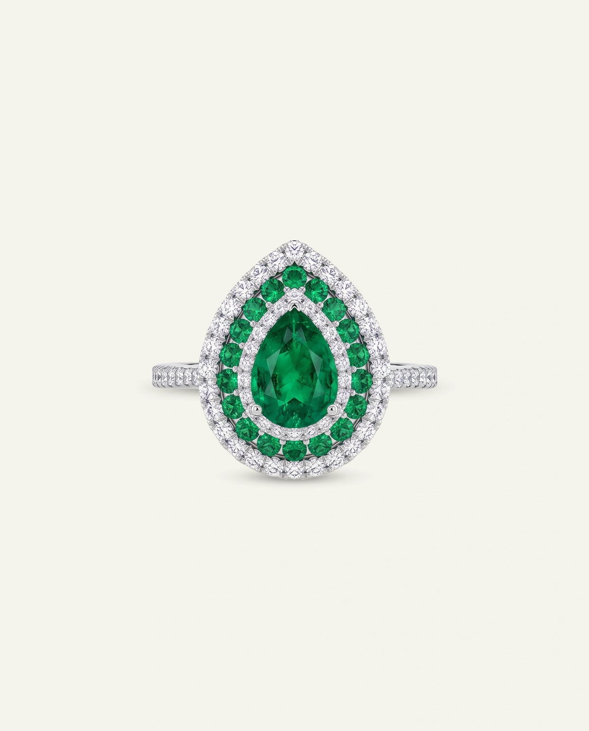 A teardrop-shaped ring featuring a large green emerald-cut center stone surrounded by a double halo of small green and clear stones on a silver-toned band, set against a light cream background.