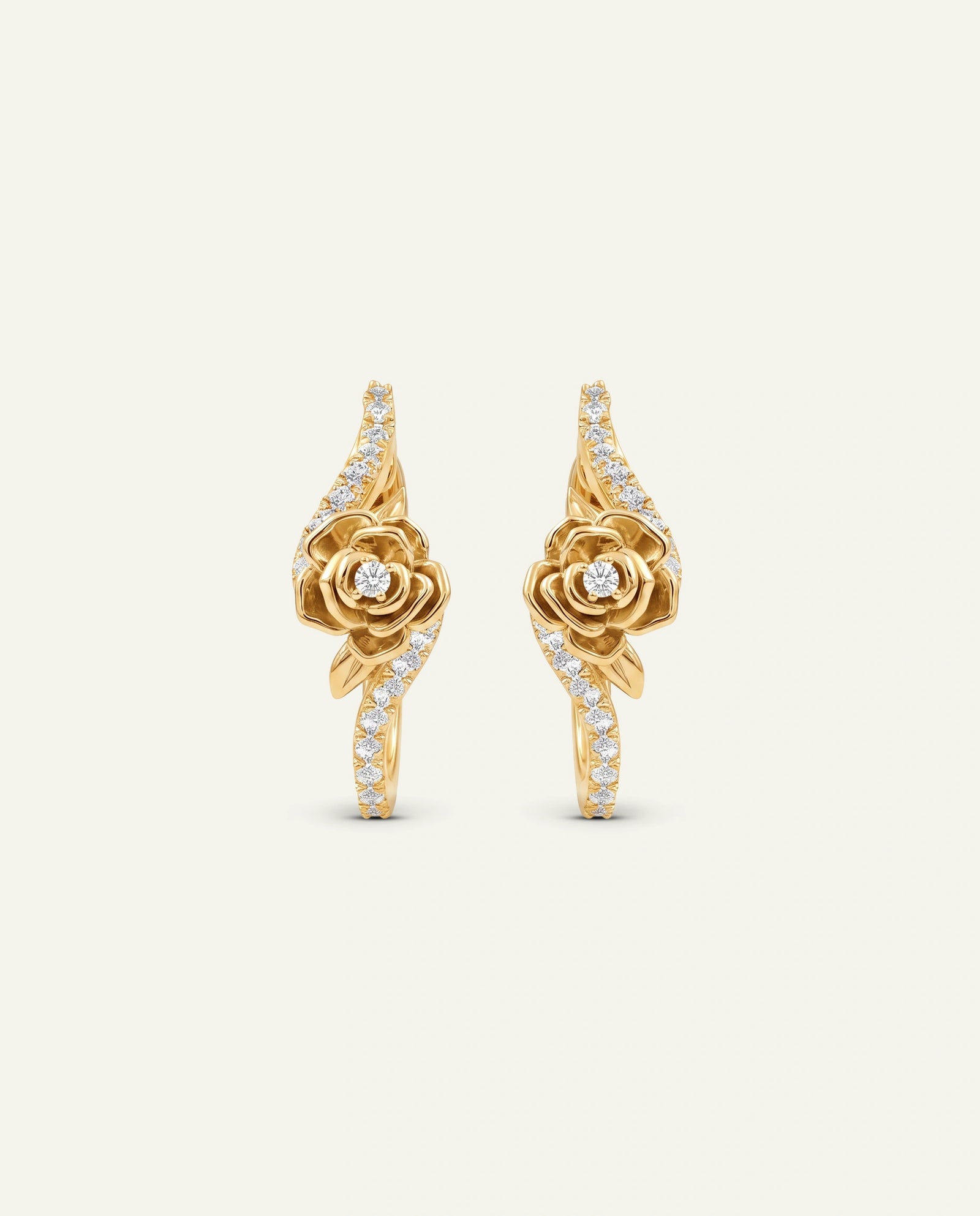 A pair of rose gold hoop-style drop earrings featuring a sculpted central rose motif with a small round diamond at the center, surrounded by curved ribbon-like bands studded with pavé diamonds, set against a plain off-white background.