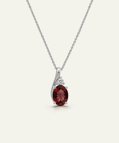 A silver pendant necklace featuring an oval deep red gemstone and small clear accent stones, displayed on a clean off-white background. - alternate view