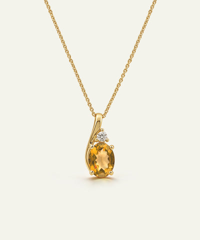 A yellow gold necklace with a curved pendant featuring a large oval-cut yellow citrine gemstone and a small clear accent stone, shown on a light cream background.