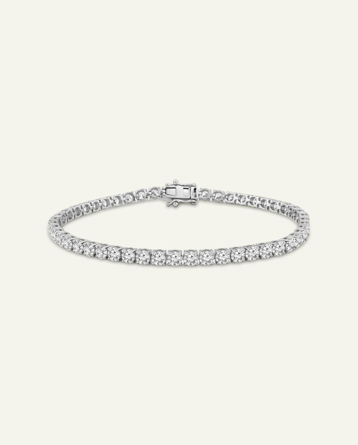 A silver tennis bracelet with a row of clear round-cut stones and a clasp, shown against a solid off-white background.