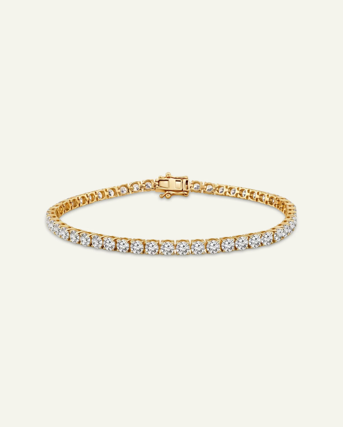 A yellow gold tennis bracelet featuring a single row of round-cut clear gemstones across the front, displayed on a light cream background.