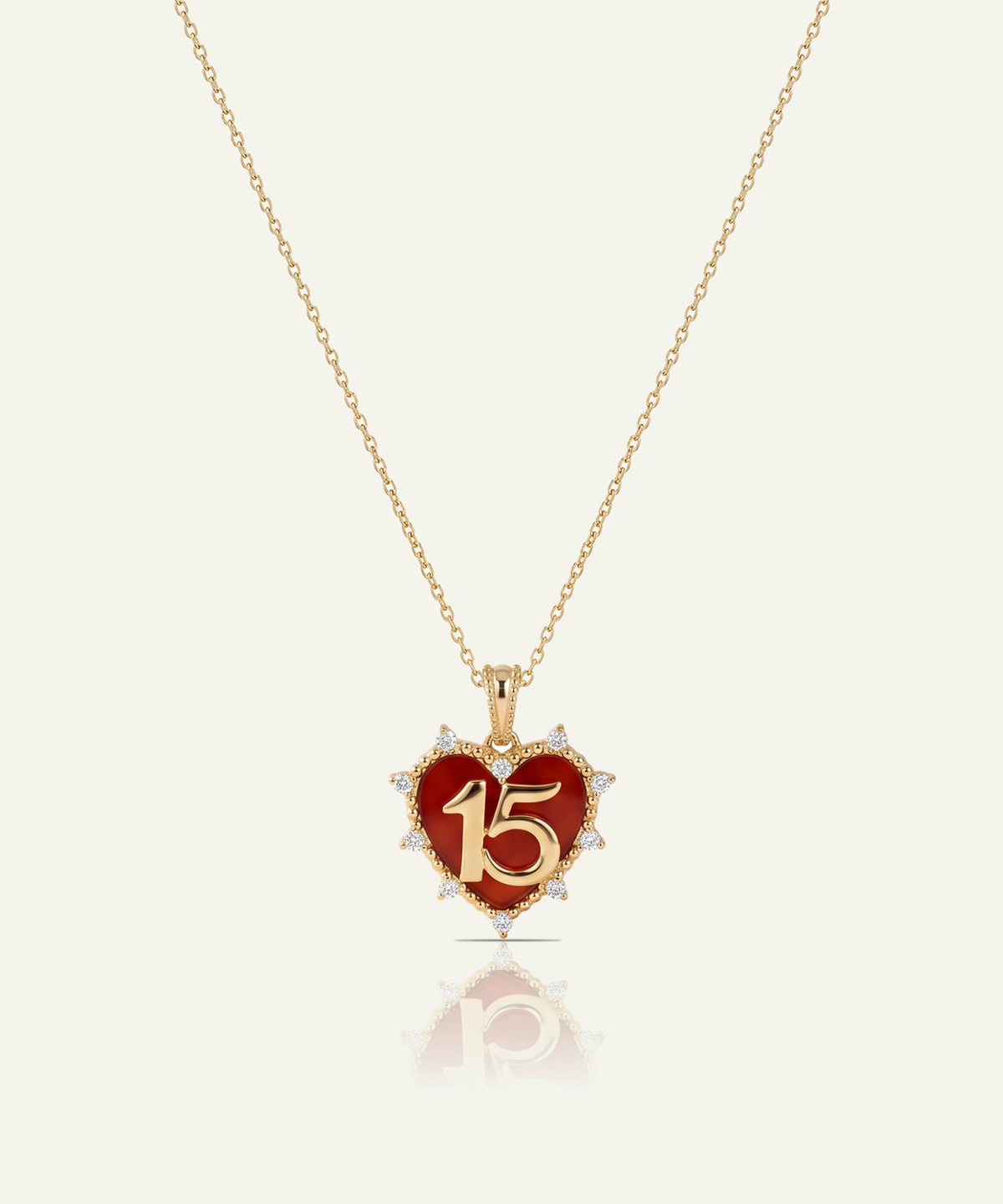 "Gold chain necklace featuring a red heart pendant with a gold '15' and diamond accents."