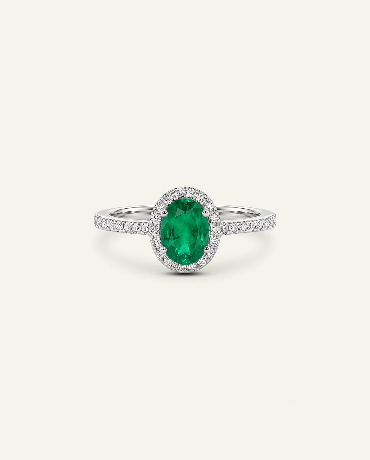 An oval emerald-cut green gemstone ring with a halo setting and a diamond-accented band, shown on a light cream background.