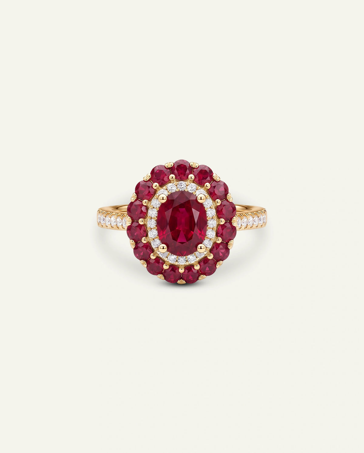 A yellow gold ring featuring an oval-cut red ruby center stone surrounded by a double halo of round red rubies and small clear pavÃ© diamonds, with a diamond-accented band, set against a light off-white background.