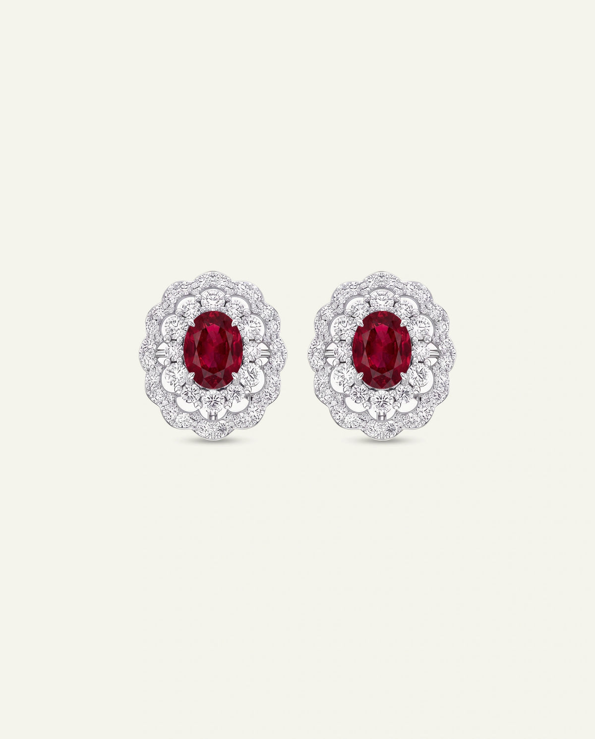Gold earrings with green and red stones on a white background