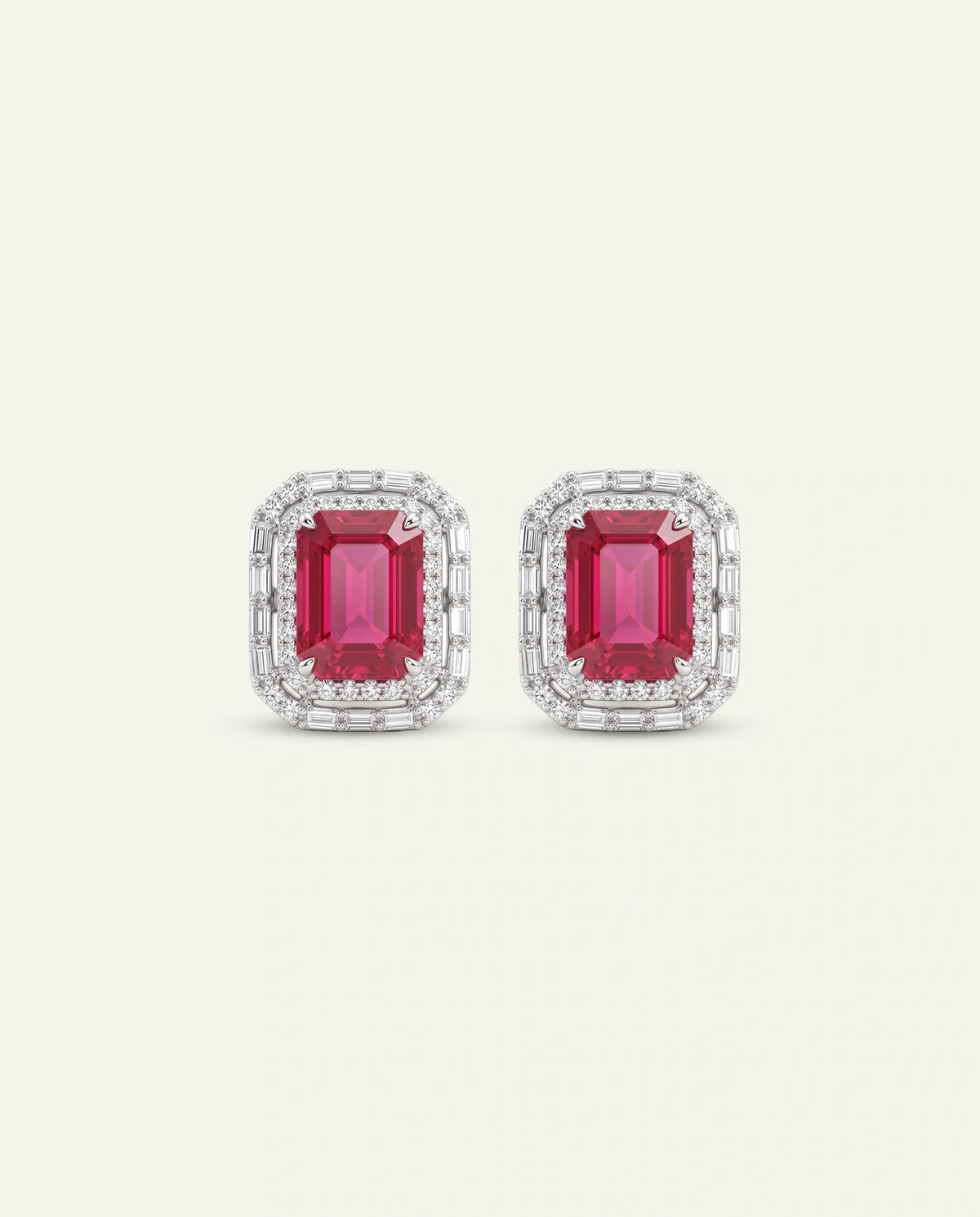 A pair of rectangular stud earrings featuring emerald-cut pink gemstones surrounded by double rows of small clear stones in a silver-toned setting, shown on a light cream background.