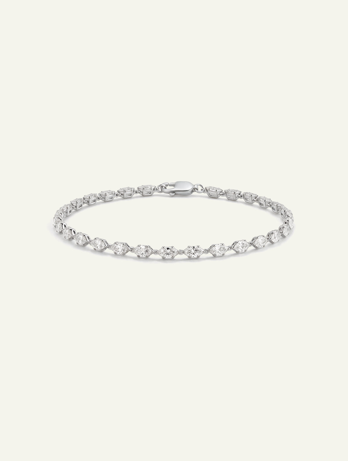 White gold tennis bracelet featuring alternating round and marquise-cut diamonds on an off-white background.
