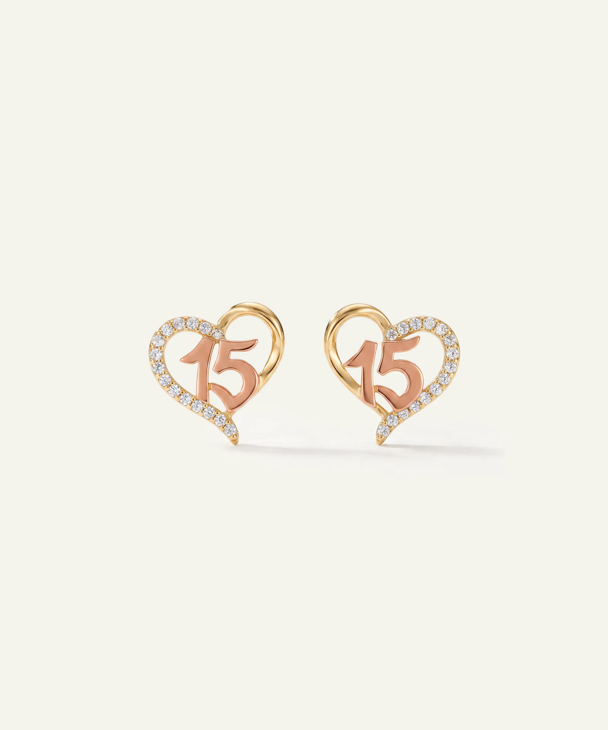"Pair of gold and rose gold heart stud earrings featuring a diamond-paved '15'."