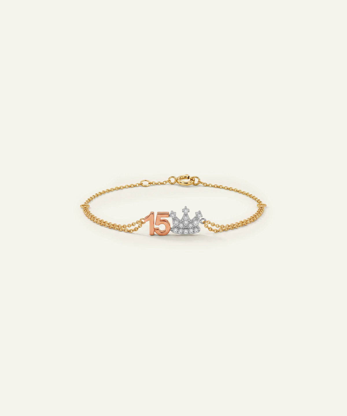 "Gold chain bracelet featuring a rose gold '15' and a diamond-paved crown charm."