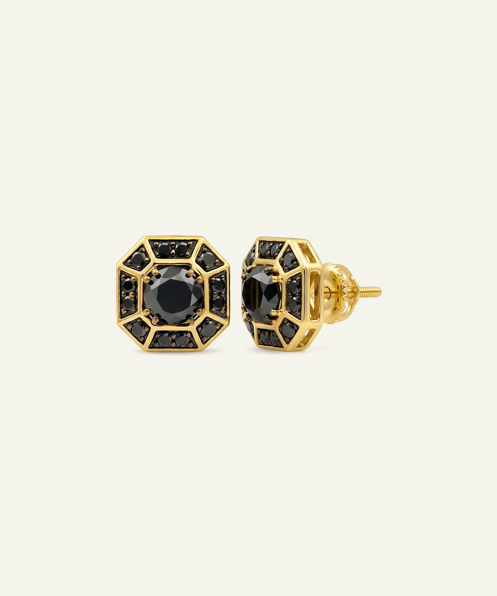 A pair of gold geometric stud earrings with black gemstone centers and surrounding halo details, shown against a plain off-white background.