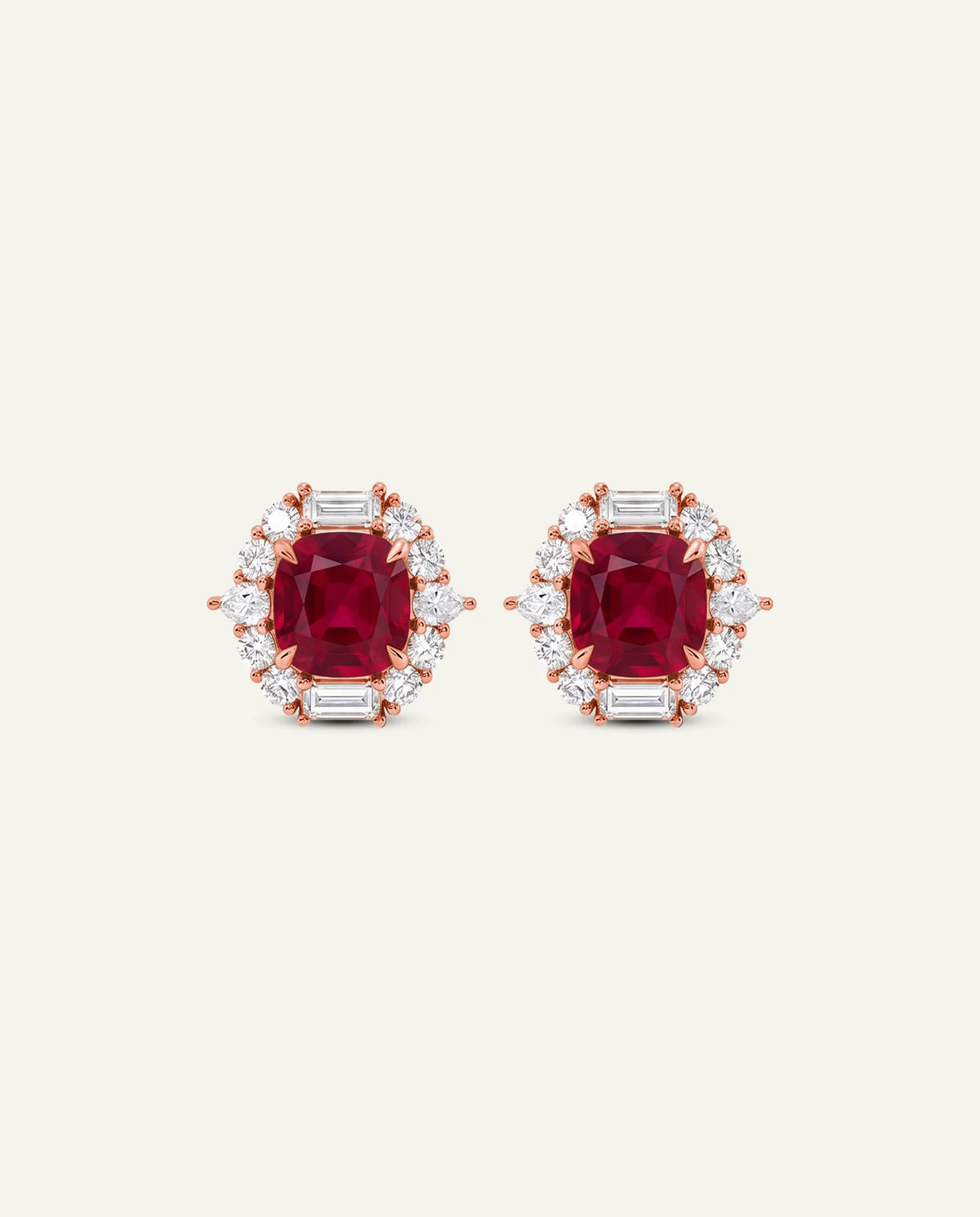 A pair of rose gold stud earrings featuring cushion-cut red gemstones surrounded by baguette-cut clear stones, set against a solid off-white background.