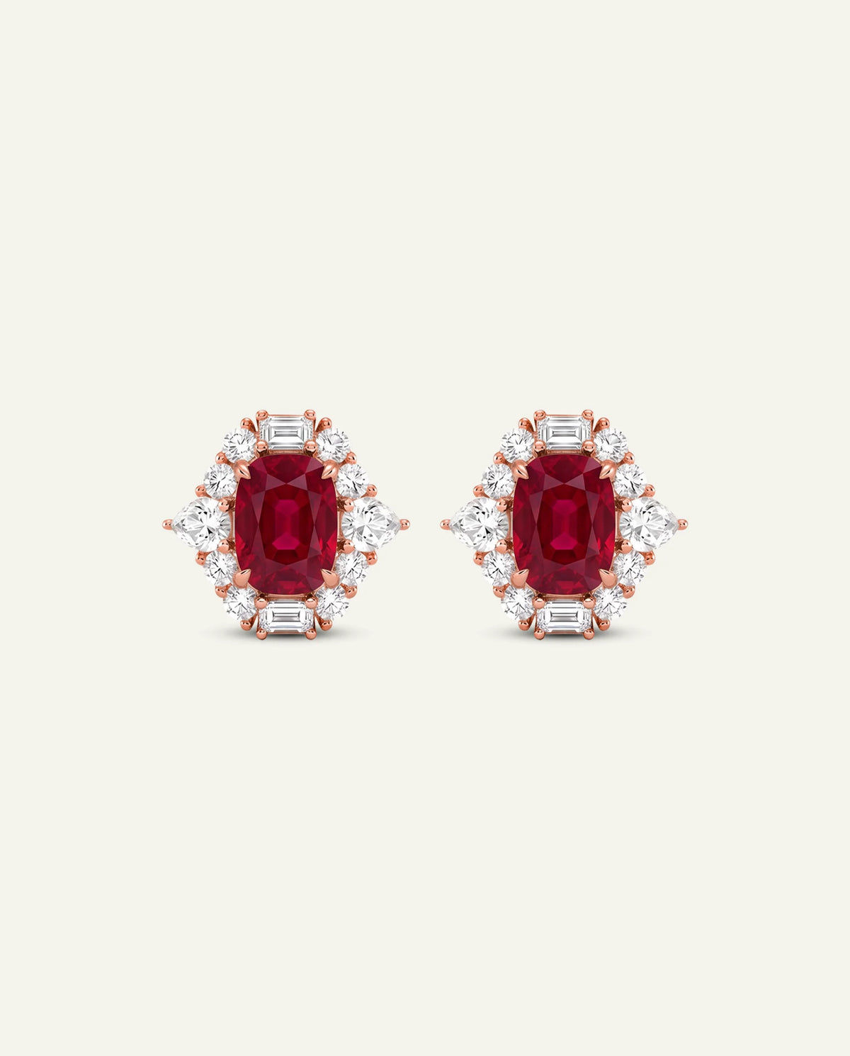 A pair of rose gold stud earrings featuring oval-cut deep red center stones surrounded by small clear baguette and round-cut stones, set against a solid off-white background.