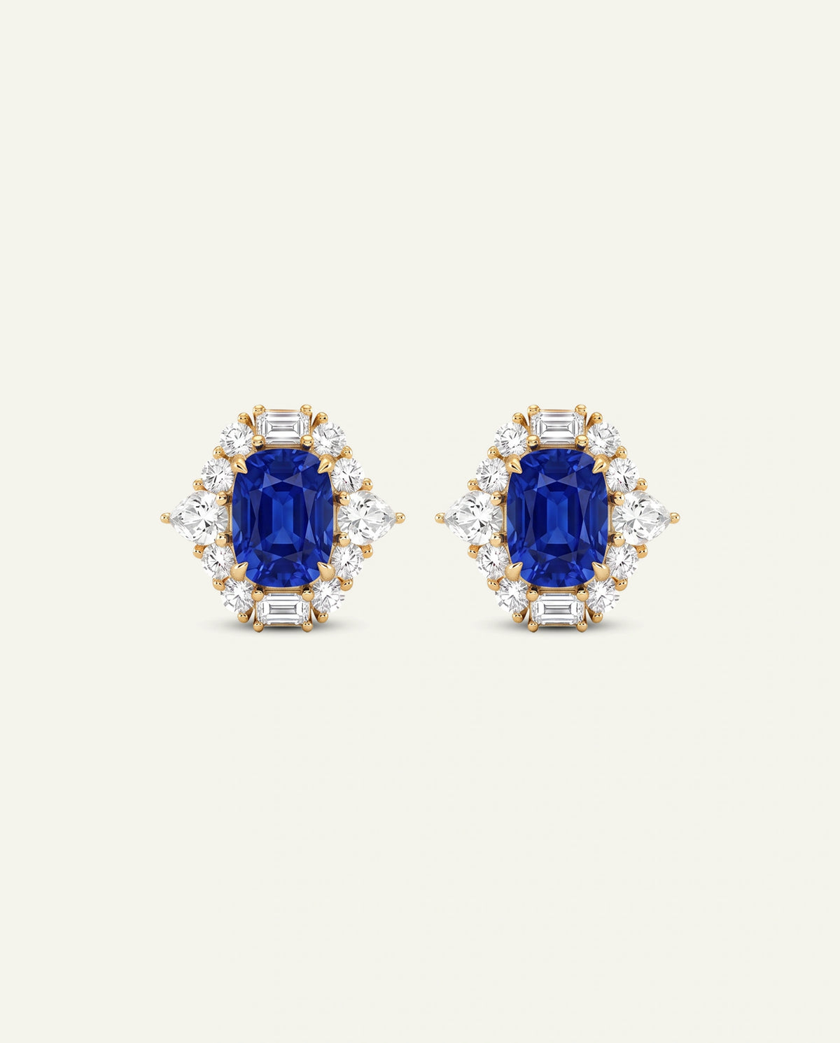 A pair of yellow gold stud earrings featuring a central emerald-cut blue sapphire surrounded by baguette and round diamonds, set against a solid off-white background.