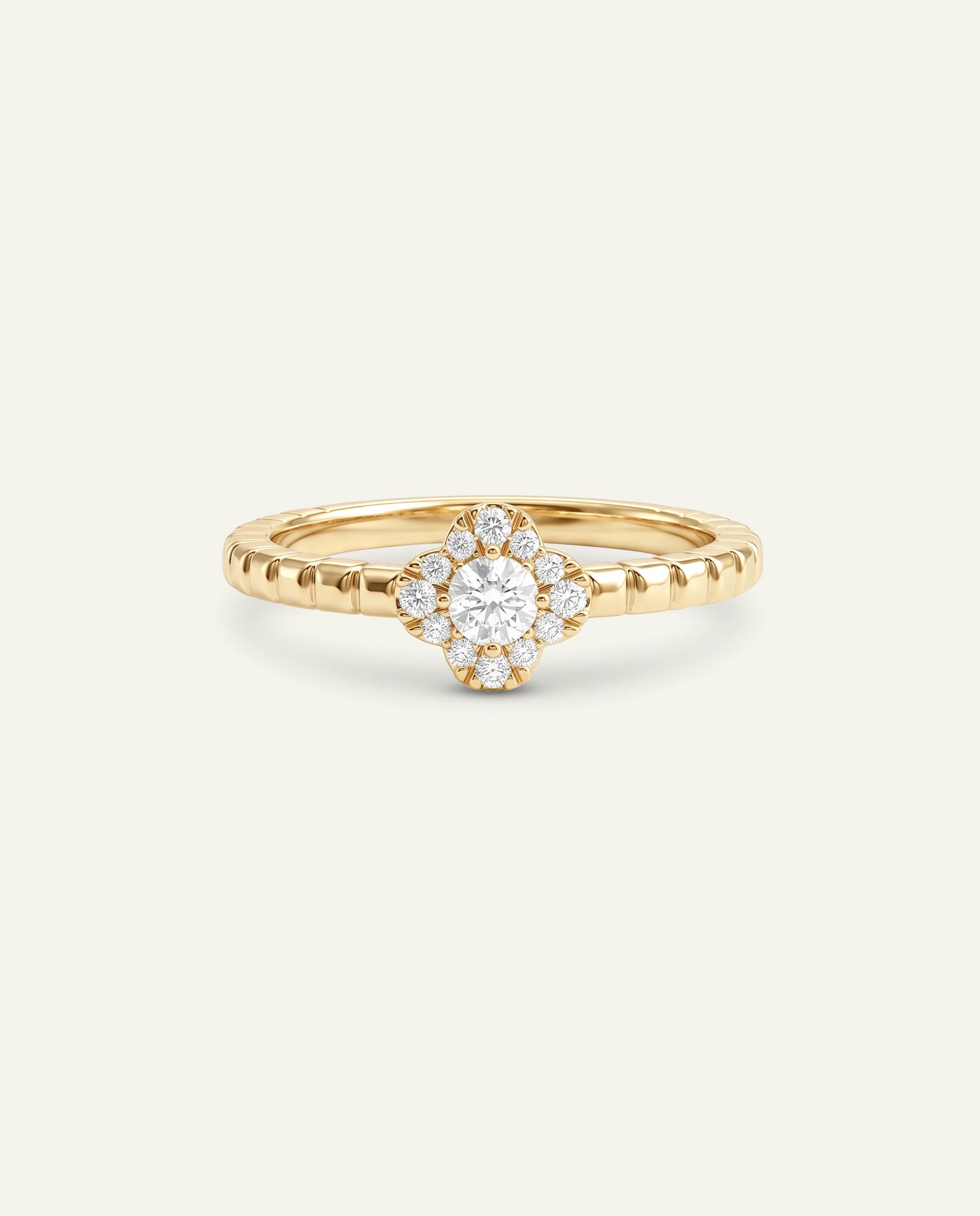 A yellow gold ring with a central round diamond surrounded by a halo of smaller diamonds, set on a textured band, shown against a light off-white background.