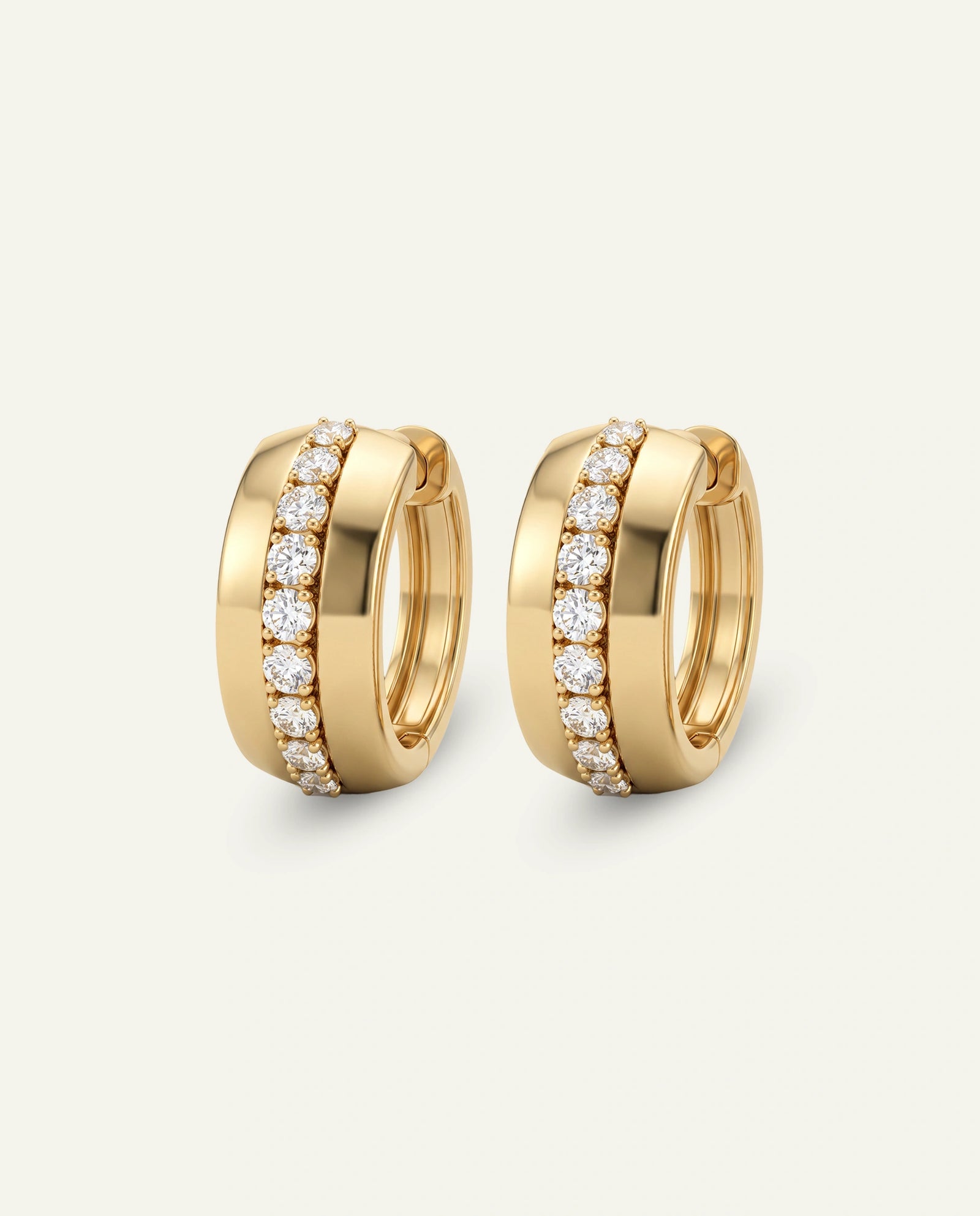 A pair of gold huggie hoop earrings with pavé-set round diamonds, shown on a light cream background.
