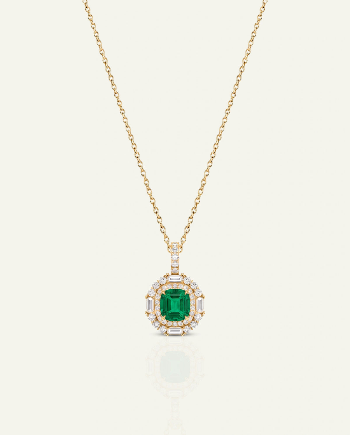 A gold chain necklace with a pendant featuring a central emerald-cut green gemstone surrounded by a halo of small clear stones, shown on a light cream background.