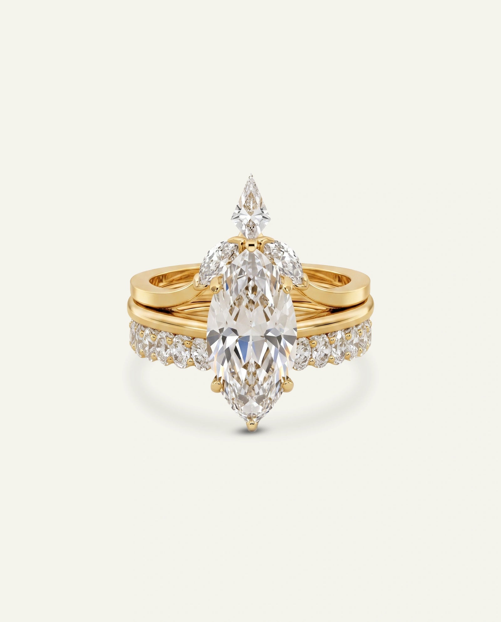 A gold ring set featuring a large marquise-cut diamond center stone with smaller diamonds along the band, photographed on a clean off-white background.