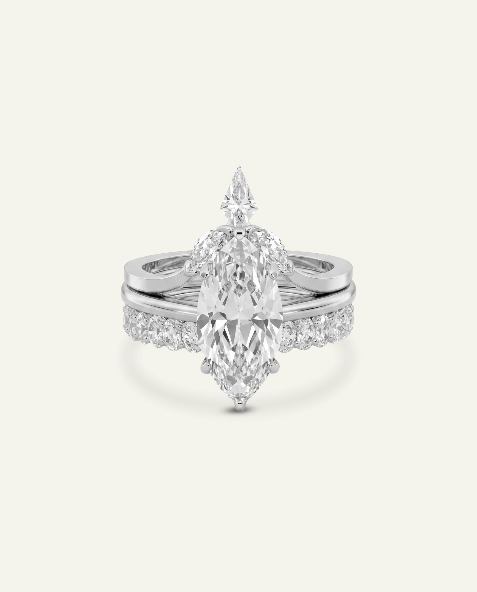 A silver-toned diamond ring featuring a marquise-cut center stone with smaller diamonds along the shoulders, shown on a light cream background.