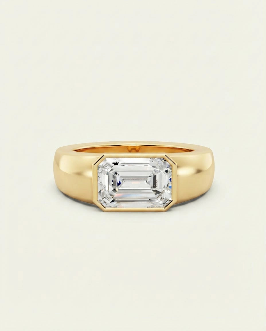 A yellow gold ring featuring a large emerald-cut clear gemstone, set against a clean, off-white background.