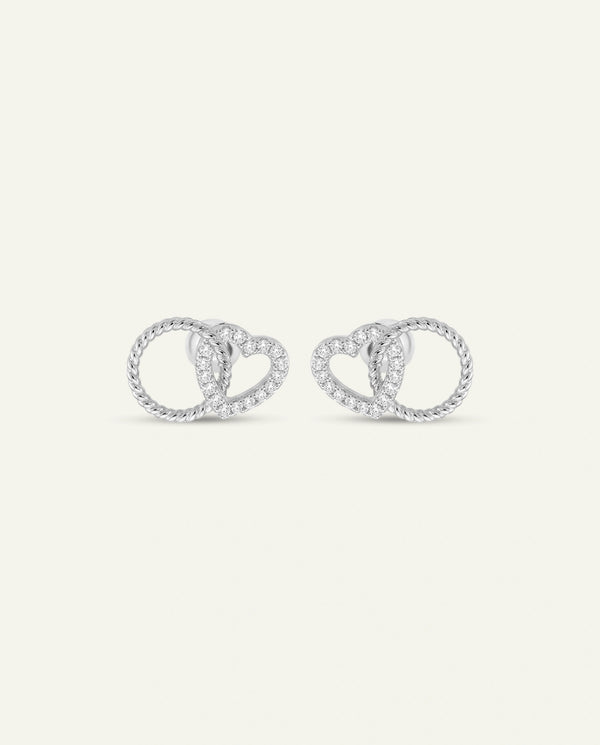 A pair of silver-toned heart and infinity loop stud earrings, set with small clear pavé stones, shown on a plain off-white background.