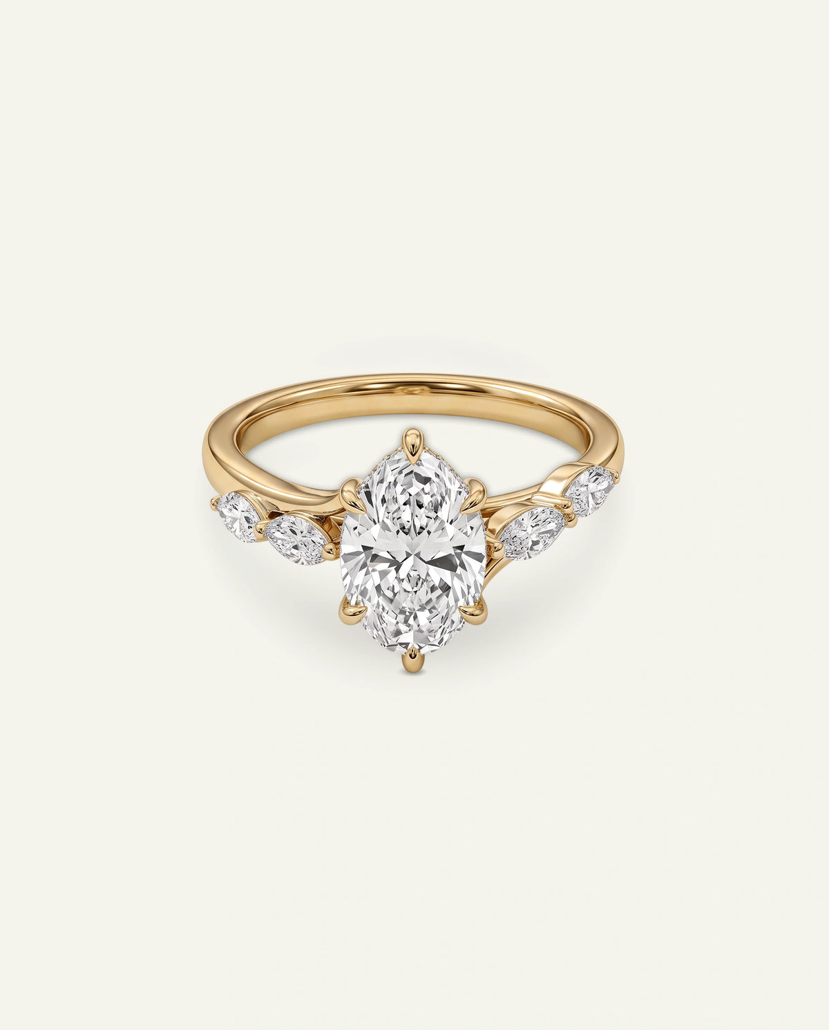 A yellow gold diamond ring with a large oval center stone and smaller marquise-cut side stones, shown on a light cream background.