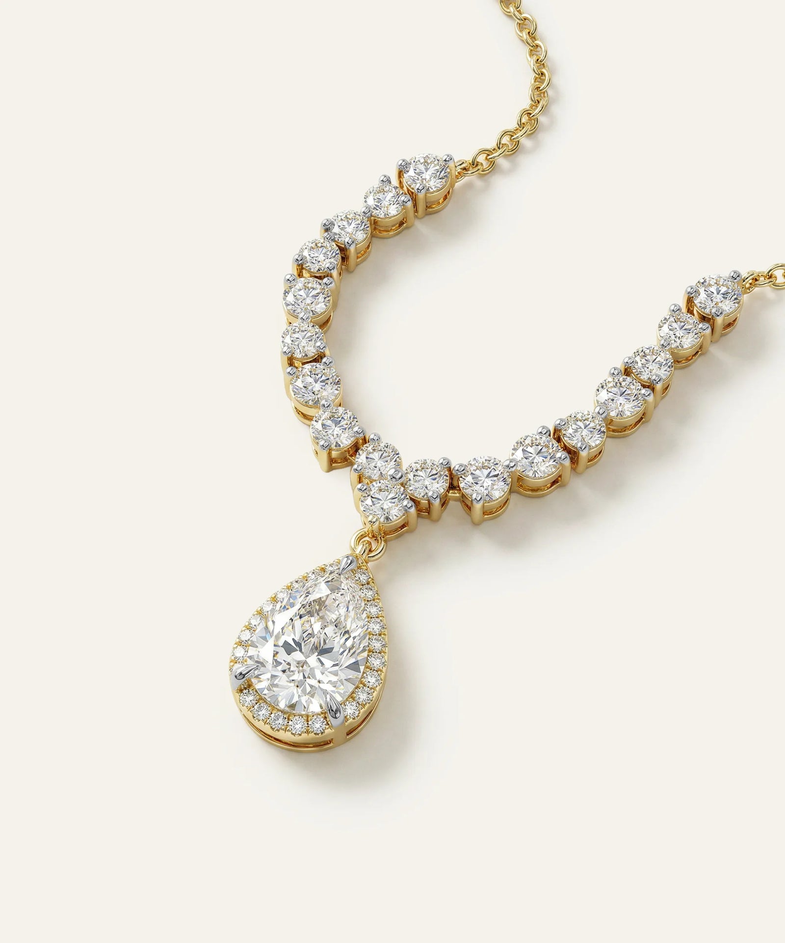 Gold necklace with a large teardrop-shaped diamond pendant on a white background