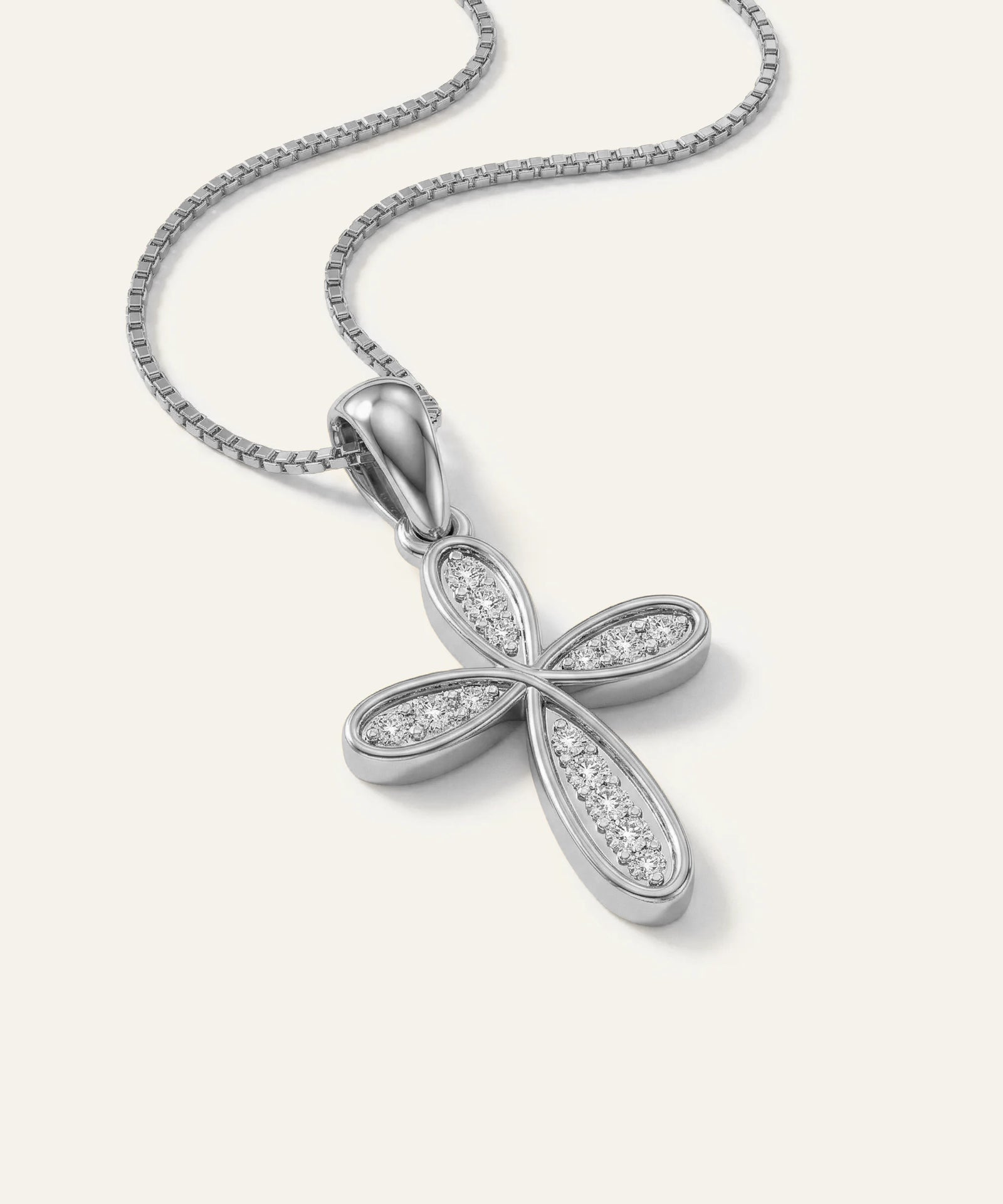Silver cross pendant with diamonds on a white chain against a white background