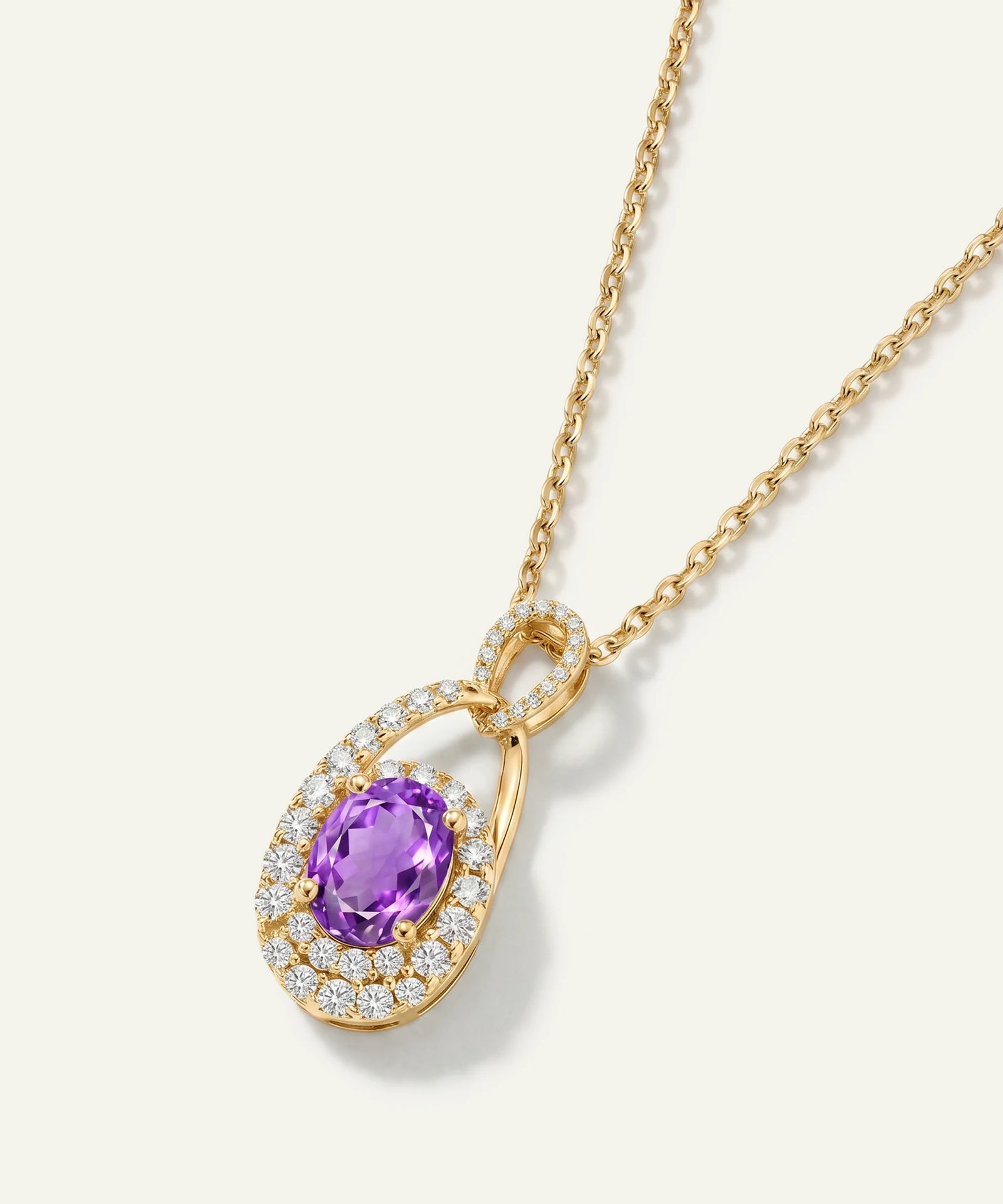Gold necklace with a purple gemstone pendant on a white background