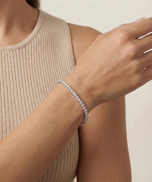 Person wearing a silver bracelet on a neutral background