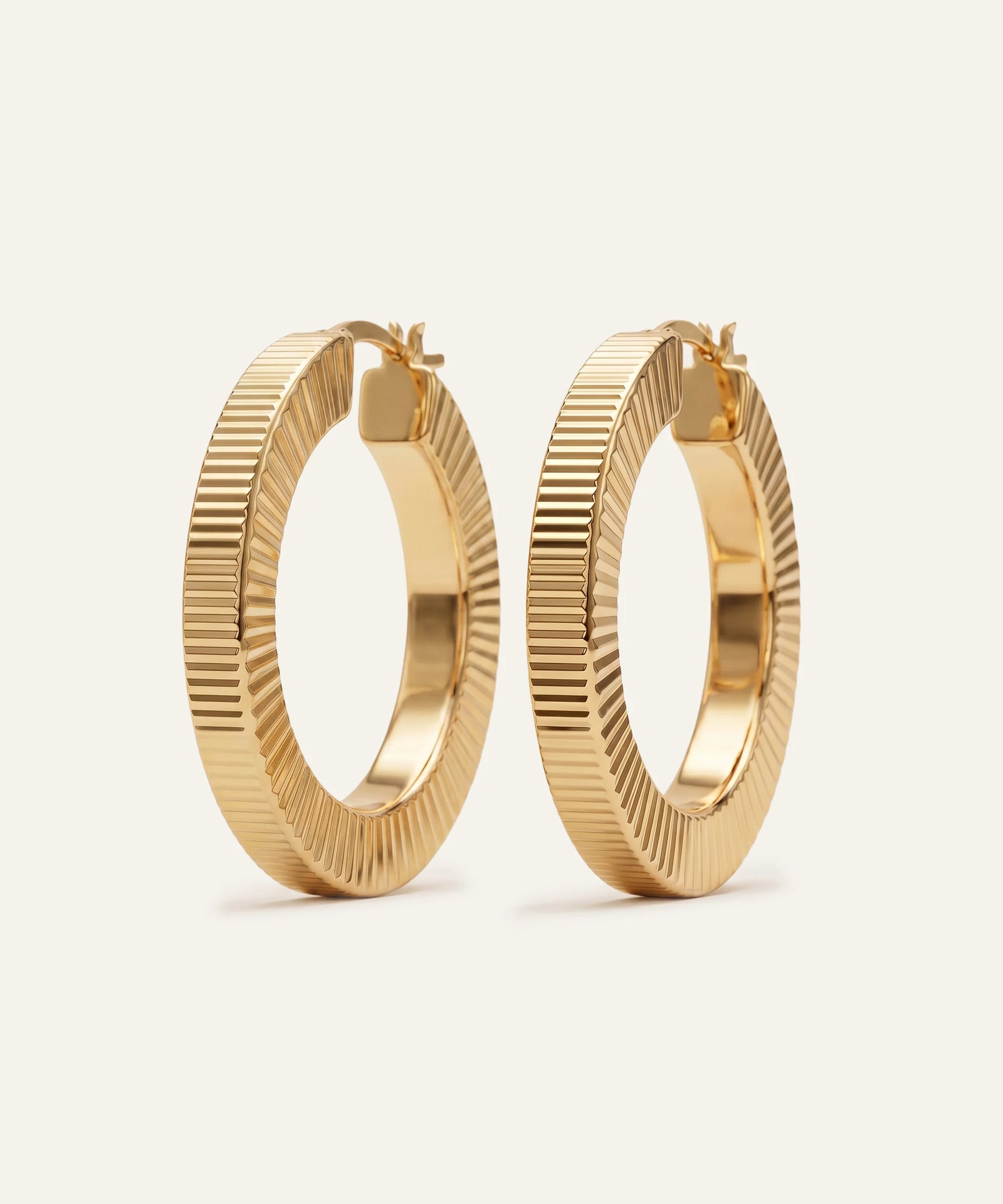 Gold hoop earrings on a beige background