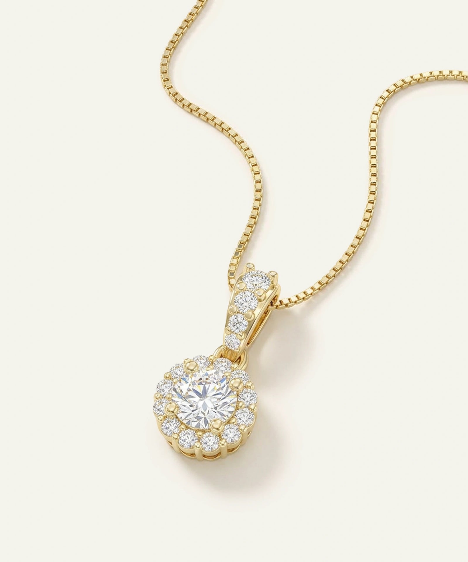 Gold necklace with a diamond pendant on a light beige background