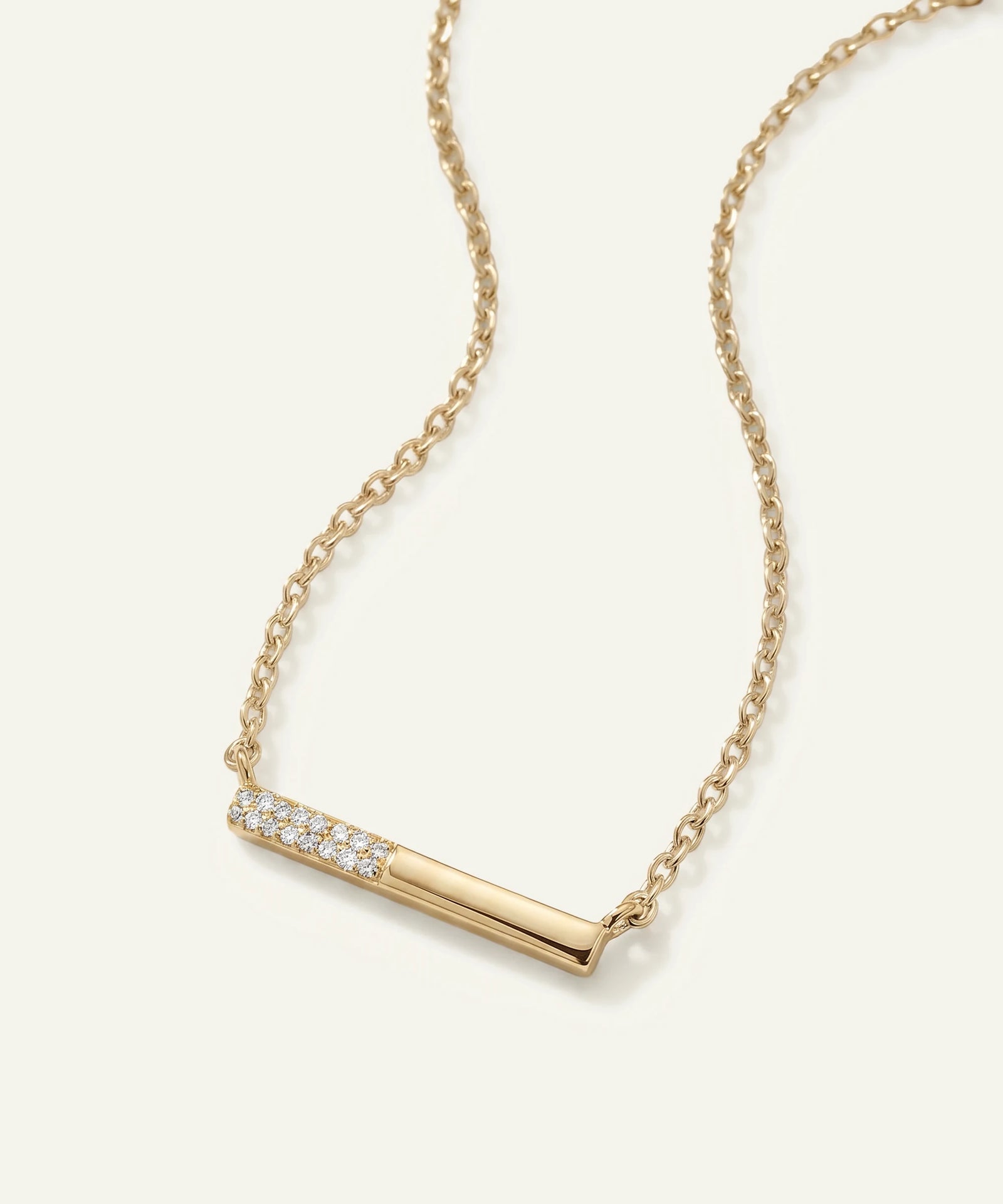 Gold necklace with a bar pendant on a white background