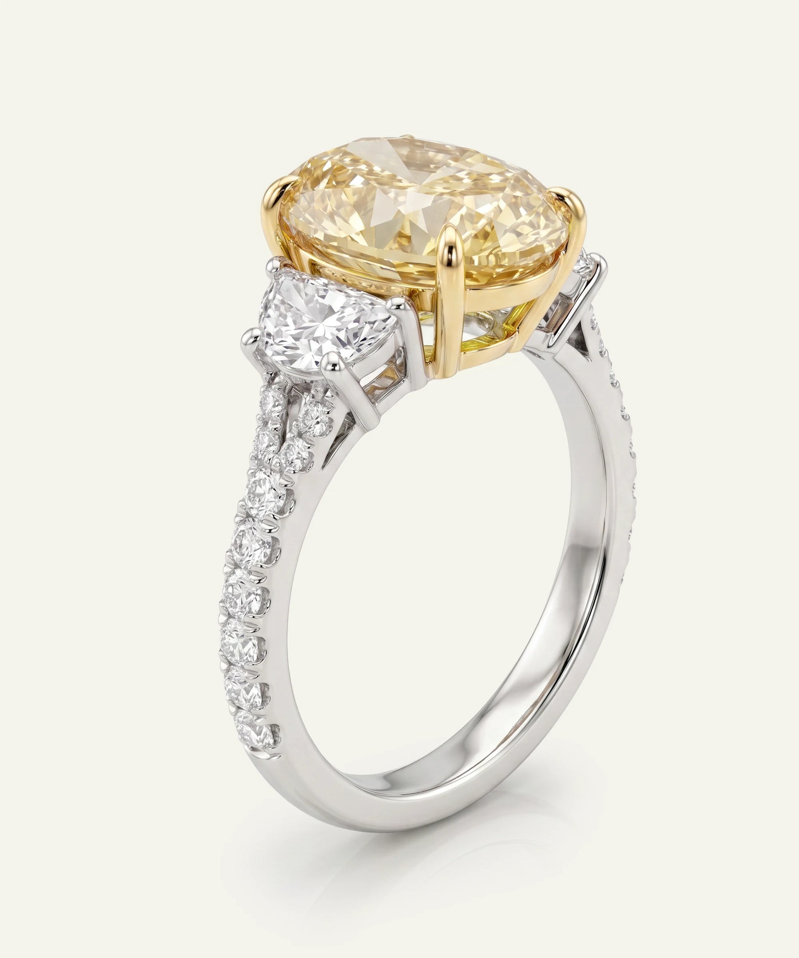 Gold and silver ring with a large yellow diamond and smaller white diamonds on a light gray background